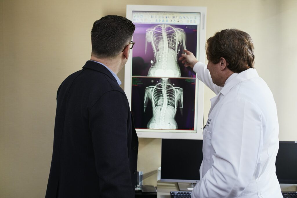 Médico analisa exames de imagem da coluna com o paciente para diagnóstico de artrose