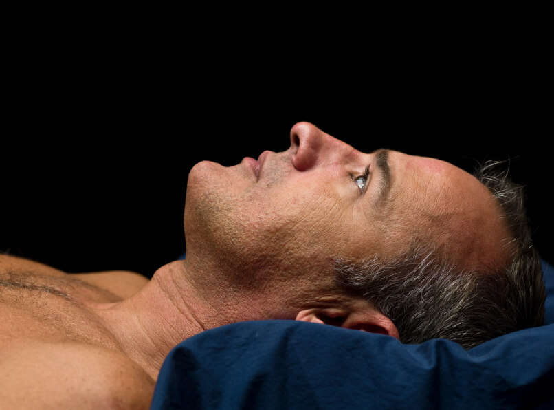 Pessoa acordada na cama à noite sem conseguir se mover, representando
um episódio de paralisia do sono.